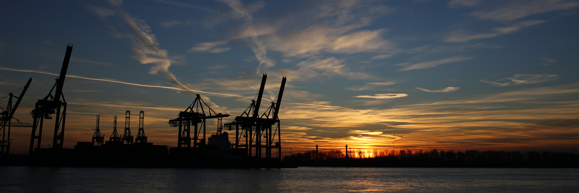 Kräne im Hamburger Hafen bei Sonnenuntergang